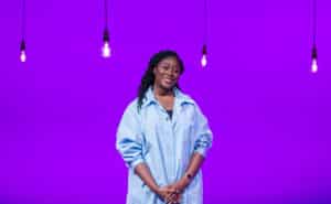 Kika Ashanike in front of a purple background with some hanging lights