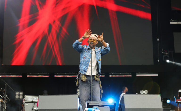 man on stage with hands in the air