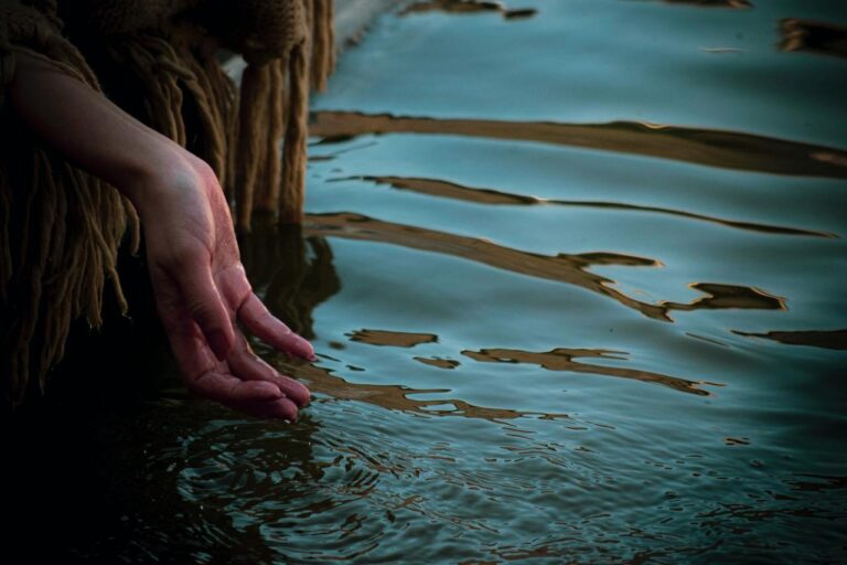 hand rippling the water of a lake