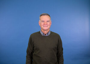 Dr John Kirkby in front of a blue background