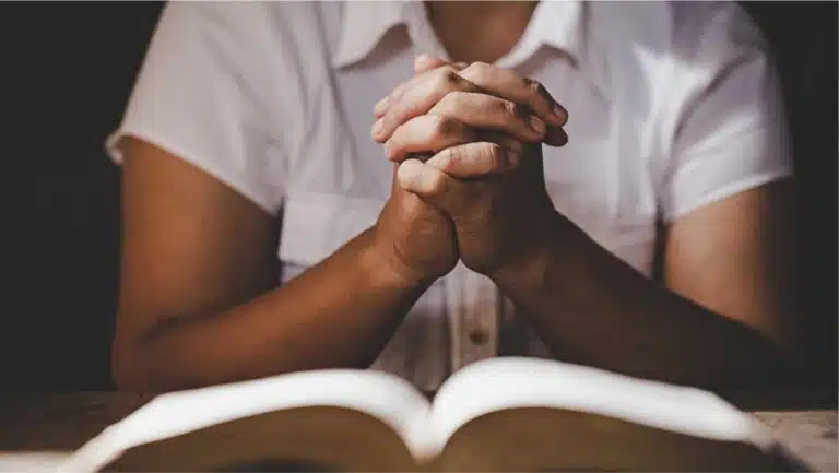 Praying hands over a Bible